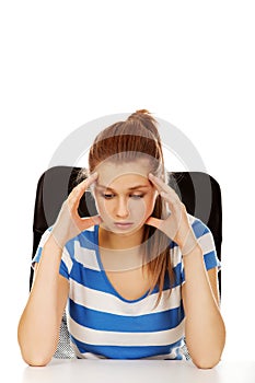 Worried teenage woman sitting behind desk