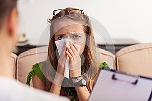 Worried teenager girl blowing nose at the counseling session. Seeking professional help and support