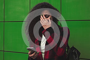 Worried teenager girl looking at her smart phone in a park with an unfocused background