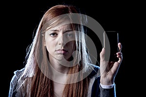 Worried teenager holding mobile phone as internet cyber bullying stalked victim abused photo