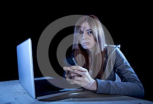 Worried teenager using mobile phone and computer as internet cyber bullying stalked victim abused photo