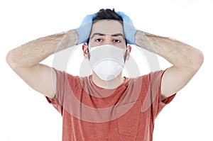 Worried and tired person with virus protection surgical face mask and gloves holding his head .
