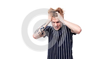 worried unhappy 25s blond man dressed in a tank top with tattoos clutching his head