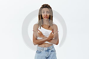 Worried unsure hesitating insecure african american young woman with cool dreadlocks frowning pointing left and right