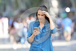 Worried woman checking smart phone messages photo