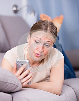 Worried woman on couch with phone