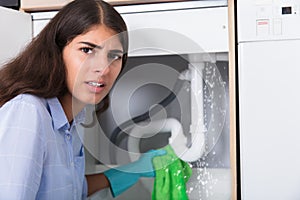 Worried Woman Holding Napkin Under Sink Pipe Leakage In Kitchen