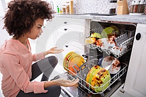 Worried Woman Looking At The Dirty Plates In The Dishwasher