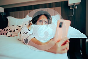 Worried Woman Looking at her phone Lying in Bed photo