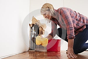 Worried woman mopping up water from a burst pipe with sponge photo