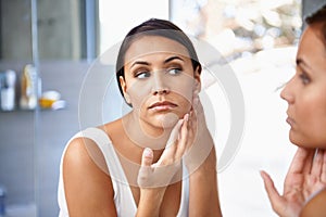 Worried, woman and skincare in mirror pimple or face spot or acne on cheek. Female person, unhappy or sad and reflection