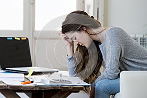 Worried woman suffering stress doing domestic accounting paperwork bills and invoices photo