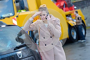 Worried woman on telephone breakdown lorry in background