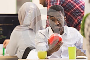 Worried young African man in formalwear checking time while look