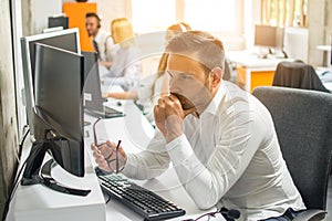 Worried young business man working on computer at office.