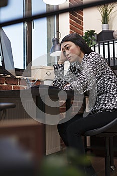 Worried young businesswoman looking helplessly at management chart on computer screen in office.