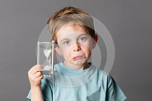 Worried young child with pouting mouth holding an egg timer