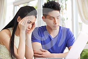 Worried Young Chinese Couple Using Laptop