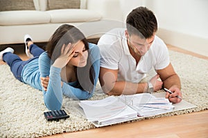 Worried young couple calculating their bills at home