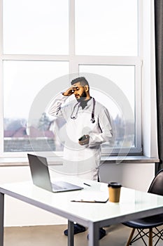 Worried young doctor sitting in his office with hands on his head