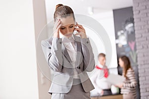 Worried young female realtor talking on smart phone while standing in apartment