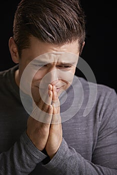 Worried young man with hands clasped, vertical portrait