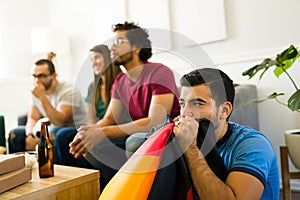 Worried young man looking anxious while watching the soccer game