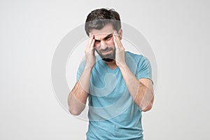 Worried young man suffering from headache holding hands on temples