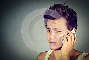 Worried young man talking on phone to someone looking upset