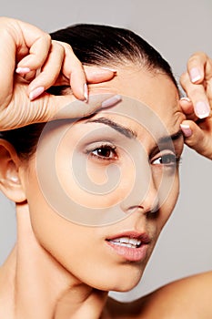 Worried young woman checking wrinkles on forehead