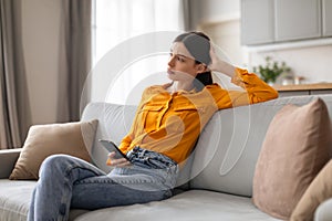 Worried young woman with phone, deep in thought