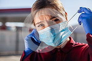 Worried young woman putting PPE face mask on/taking it off in public