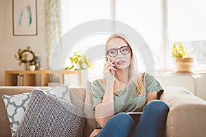 Worried young woman talking on mobile at home