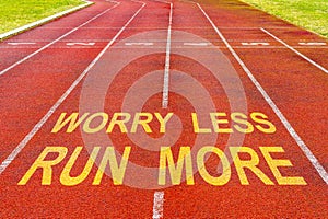 Worry Less Run More written on rubberized running track