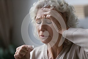 Worrying middle aged grandmother taking pills painkiller.