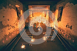 Worship in mysterious church interior with lighting candles and cross