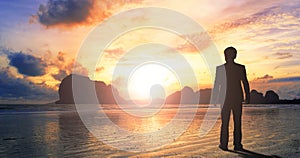 Worship and praise concept: businessman standing by the sea at sunset