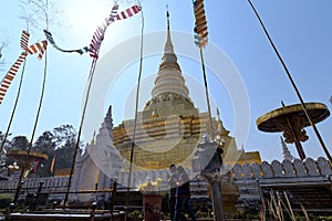 Worshippers paying respects, circumambulating the golden gilded stupa at Wat Phra That Chae Haeng, a Thai Buddhist temple in Nan