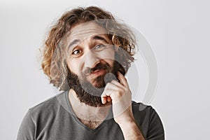 It would be problematic. Portrait of hesitating unsure eastern man scratching beard and lifting eyebrows with doubtful photo