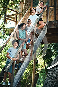 Would you like a tour of our treehouse. a group of teenagers standing next to a treehouse at summer camp.