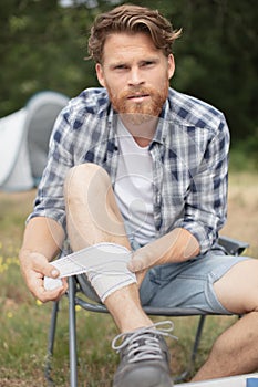 wounded man bandaging leg while on camping