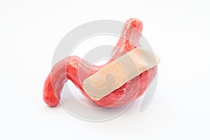 Wounded stomach. Anatomical shape of human stomach with strip of adhesive bandage or plaster on it. Concept photo damaged gastric photo
