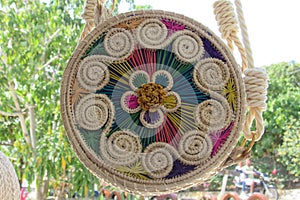 Woven basket hanging from a hook with a colorful pattern