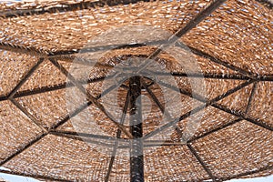 Woven beach umbrella against the sky, bottom view