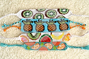 Woven DIY friendship bracelets handmade of embroidery floss with knots, alpha fruit patterns
