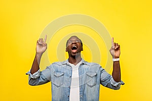 Wow, advertise there! Portrait of surprised happy man pointing up. studio shot isolated on yellow background