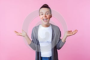 Wow awesome! Portrait of happy surprised brunette teenage girl standing with arms raised and mouth open in amazement. indoor