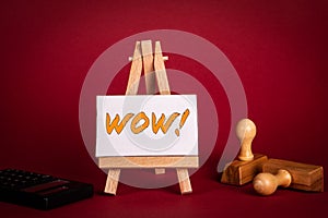 WOW concept. Miniature easel with text on a red background
