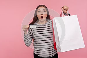 Wow credit for purchase! Portrait of amazed shocked woman holding big shopping bag and bank card, showing packages