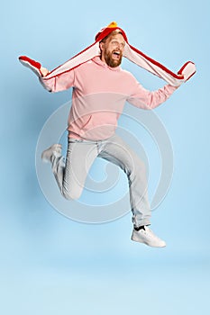 Wow, football fans emotions. Happy bearded man in casual style clothes jumping over blue background. Concept of vivid